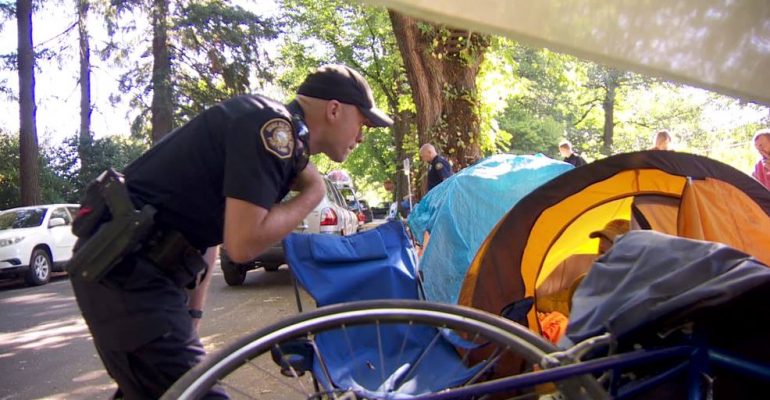 Portland Police Officer conducts a sweep of a homeless camp.