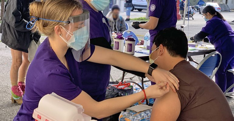 Student nurses from the University of Portland administer a flu vaccination to a man experiencing homelessness during an outdoor clinic held at Blanchet House in Oct. 2020.