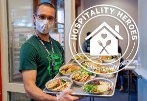 Man holding a tray of food for Blanchet House Hospitality Heroes Monthly Giving Club