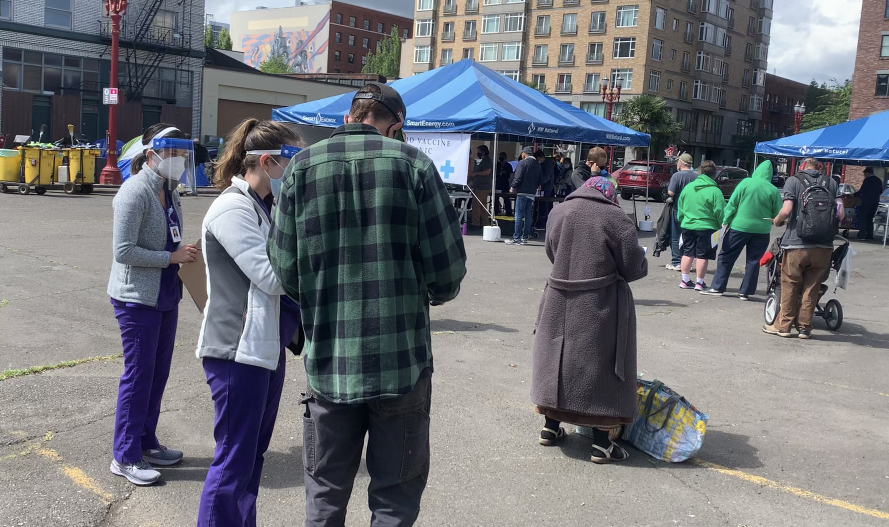 Student nurses from the University of Portland help patients fill out forms to receive a COVID-19 vaccine at an outdoor clinic hosted by Blanchet House and the Harrington Health Clinic on May 19, 2021.