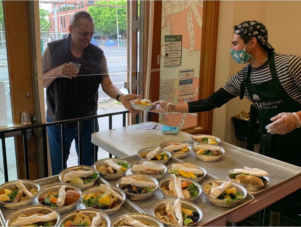 A volunteer serves a hot meal to a guest at Blanchet House of Hospitality in Portland.