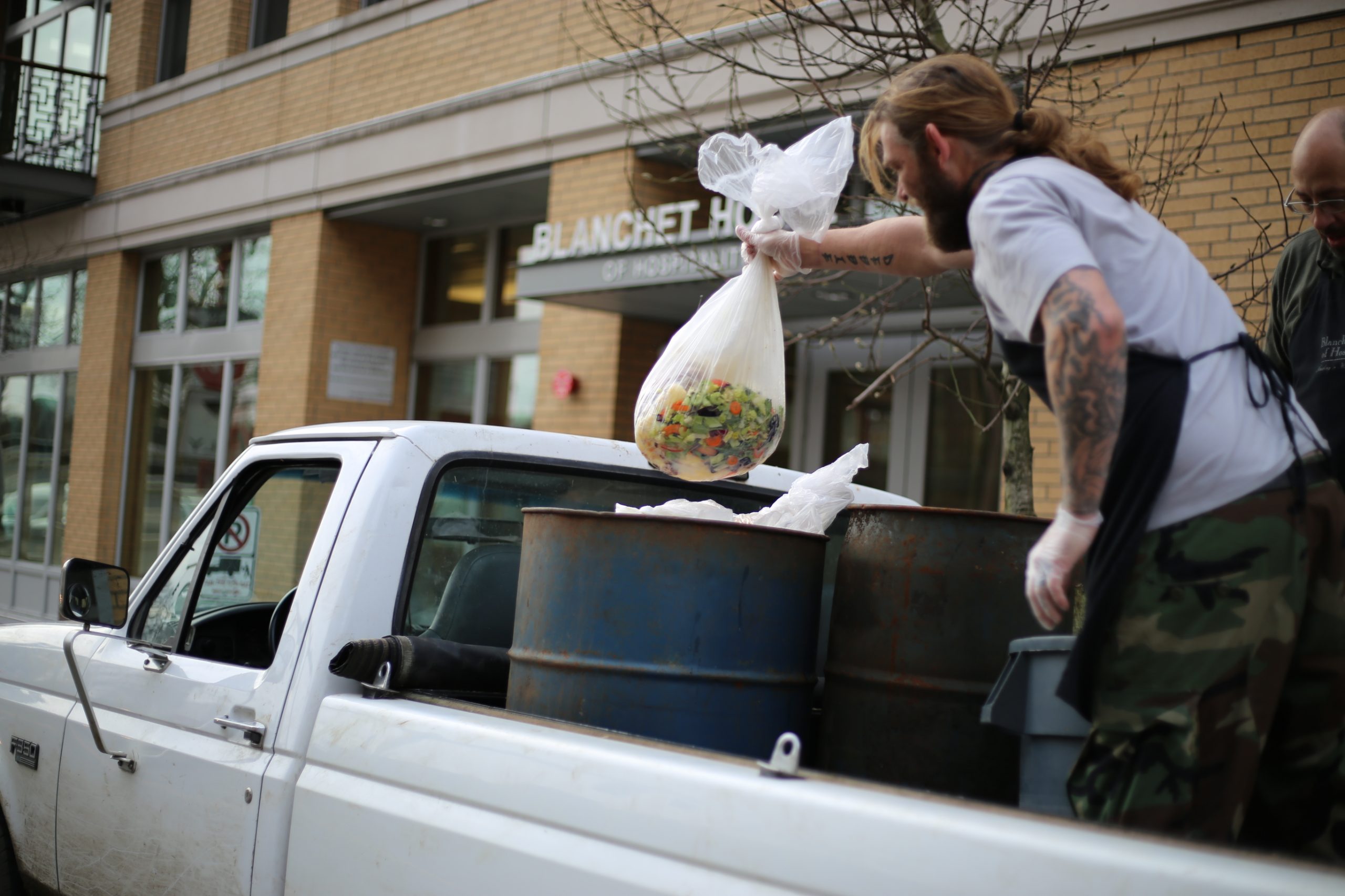 A resident of Blanchet House loads food scraps on to a truck to help the nonprofit kitchen be more sustainable.