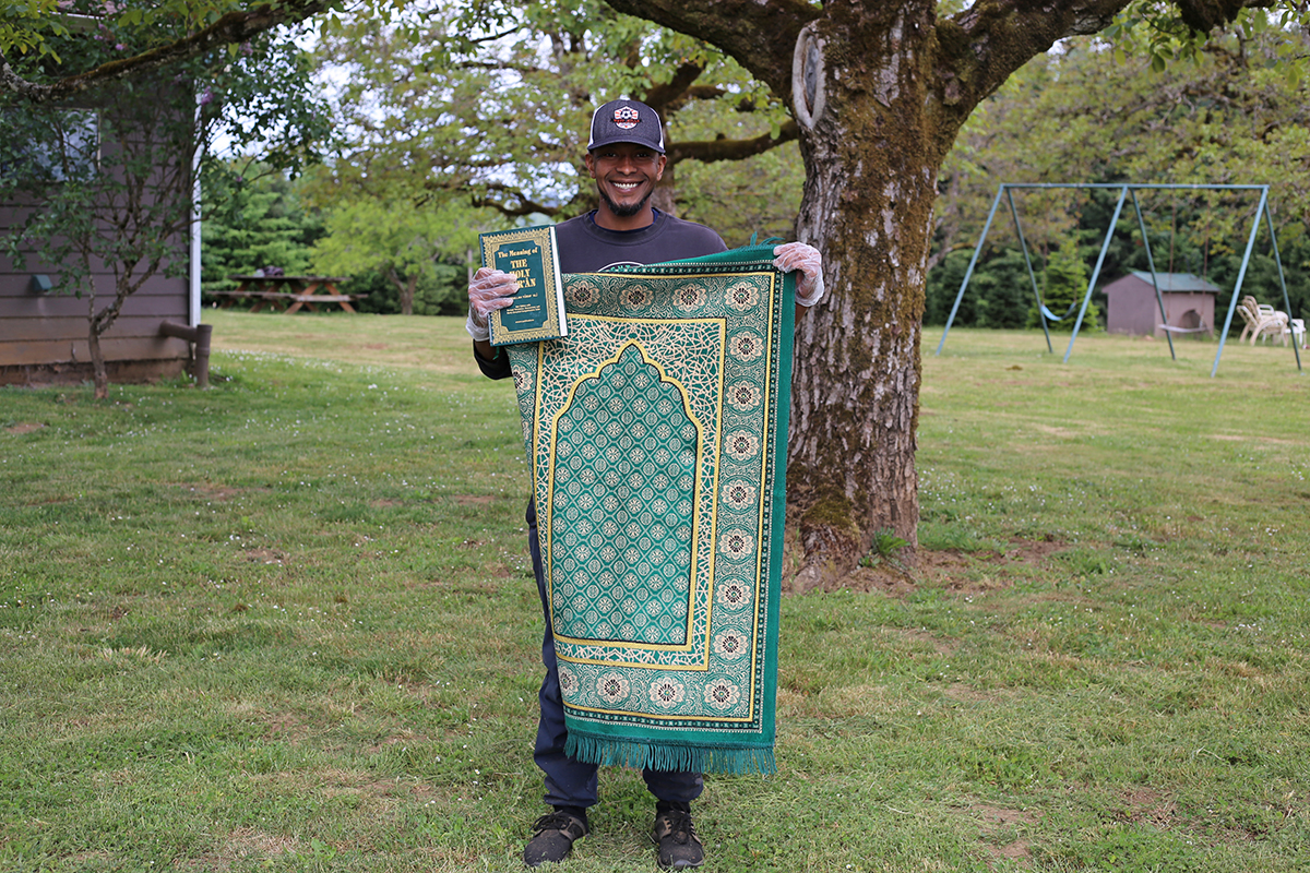 Ibrahim holds his prayer rug and Koran at Blanchet Farm.