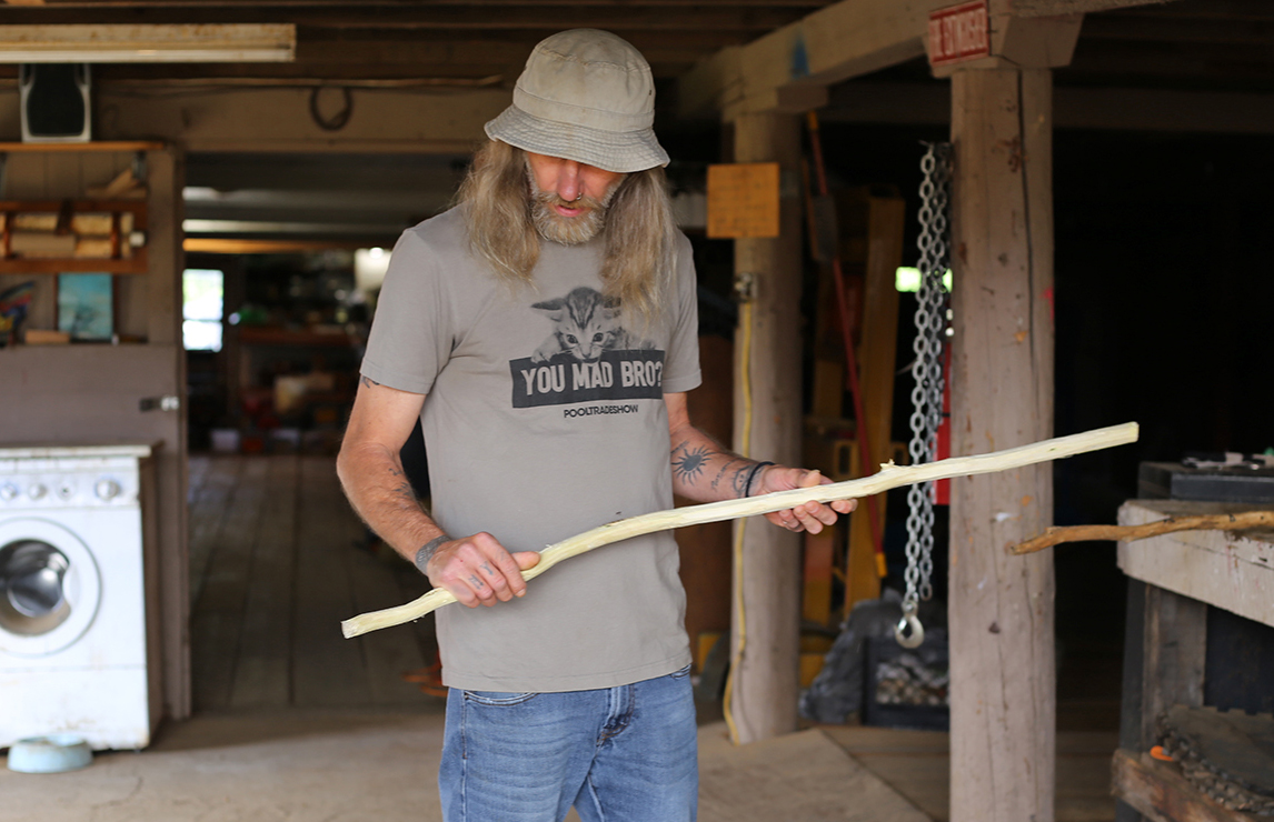 Jim holds a walking stick he's whittling at Blanchet Farm in Oregon. 