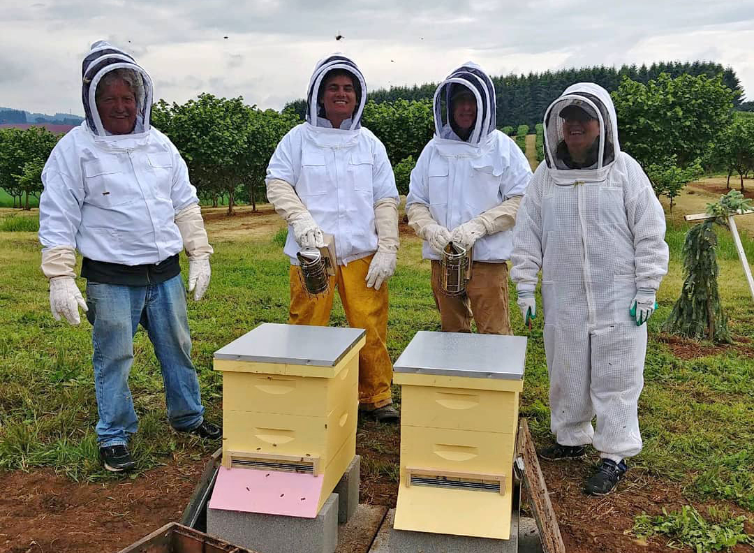Left to right: Ron, Jordan, an anonymous guest, and Katy Fackler pose next to the hives they installed at Blanchet Farm. Photo courtesy of Blanchet House.