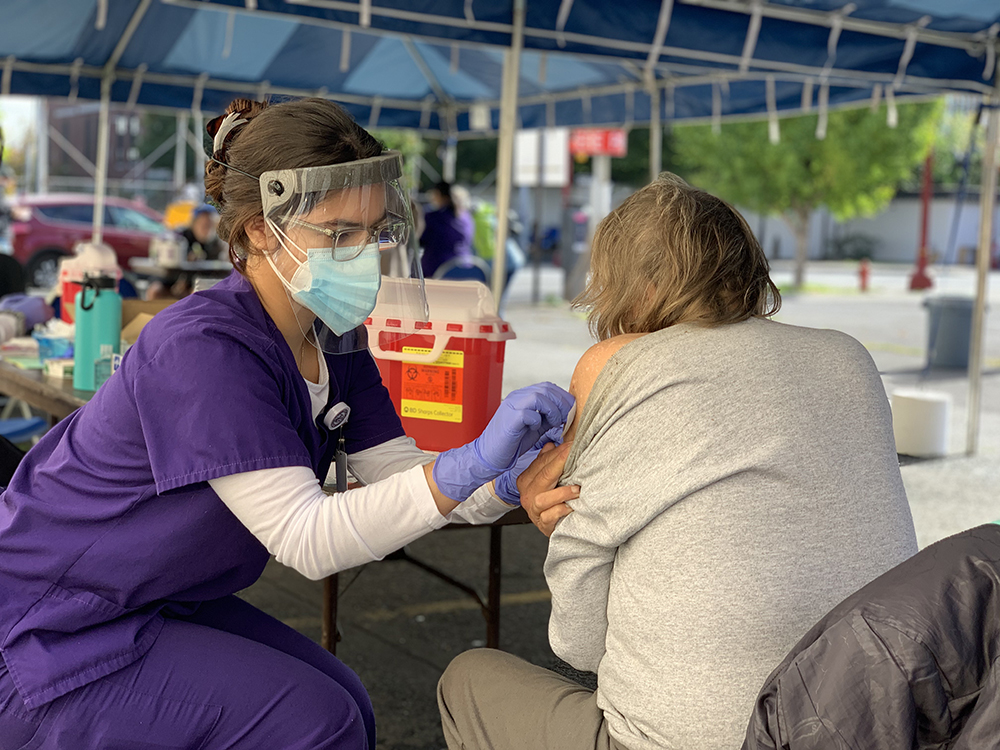 A student nurse from the University of Portland administers a flu vaccine to a meal guest in the Blanchet House parking lot, Oct. 2020.