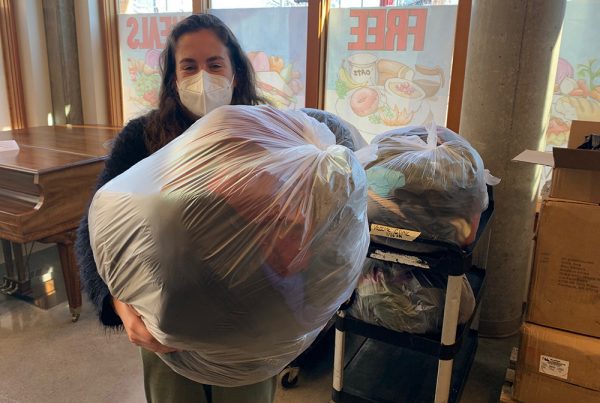 Woman holds bag of clothes that a partner recycles into cleaning cloths