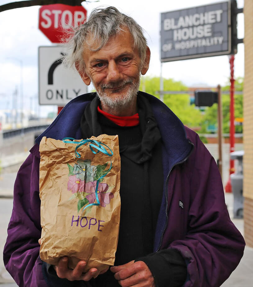 A Homeless man holds a sack lunch outside Blanchet House.