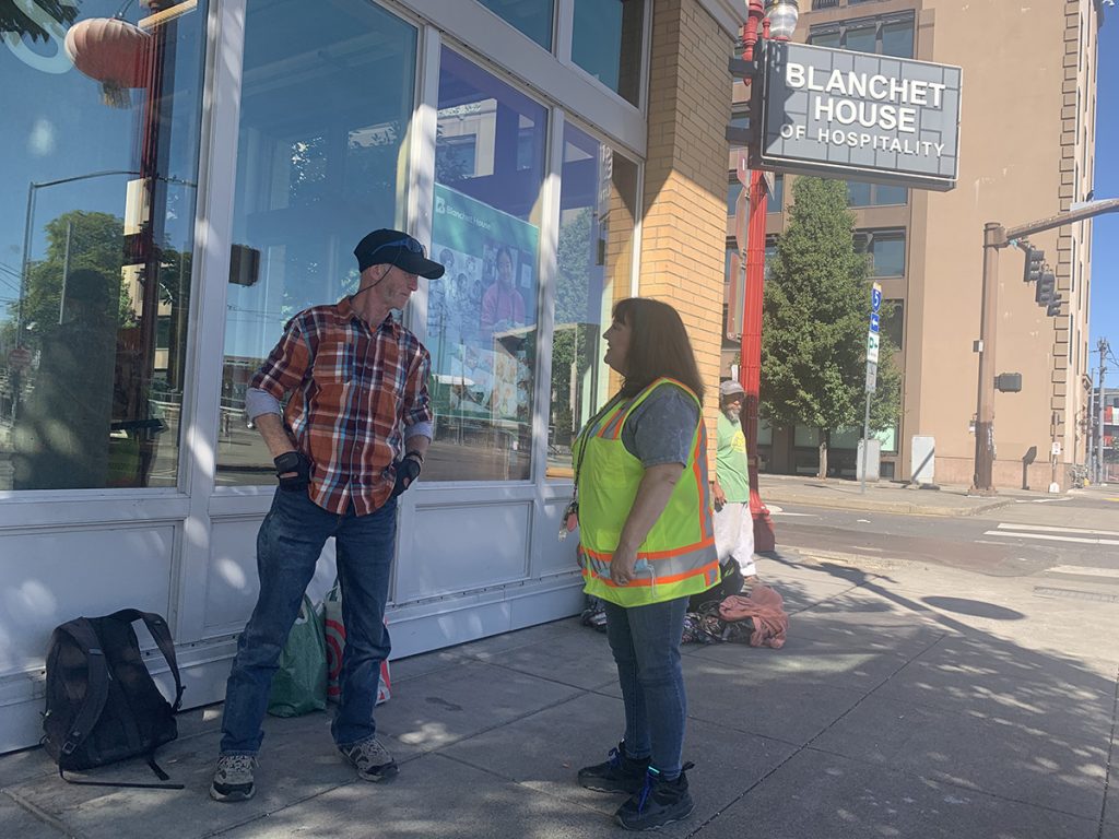 Peer Support Specialist Jennifer Coon talks to homeless man outside Blanchet House