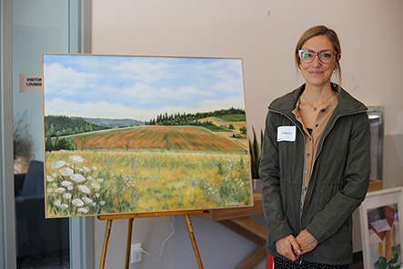 Pictured: Newberg, Oregon-based artist Angelina Octavia stands next to her oil painting of the landscape surrounding Blanchet Farm. The painting will hang in the new facility and prints will be given to donors.