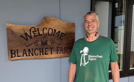 Pictured: William, a resident of Blanchet Farm, stands next to the welcome sign made by previous resident Lucas Pattison. William spoke at the grand opening of Blanchet Farm's new facility and delivered a land acknowledgment.