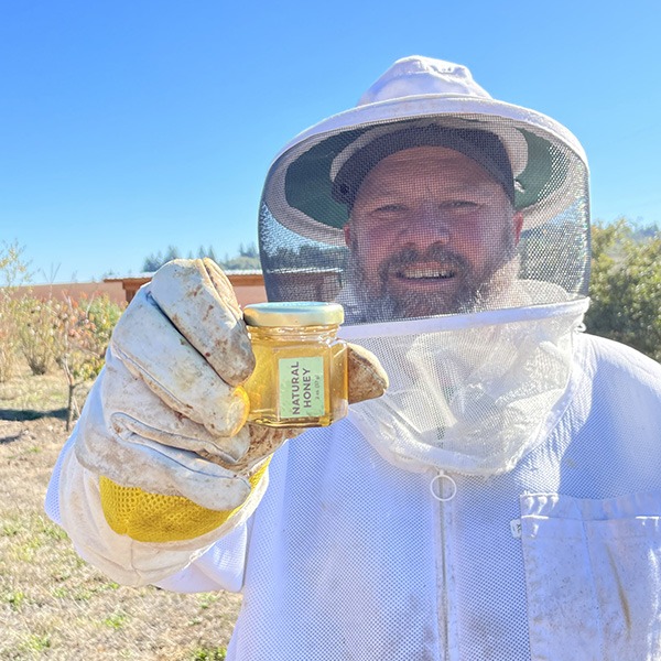 Greg Vergets holds a jar of honey he helped to produce as a participant in Blanchet Farm's beekeeping program. 