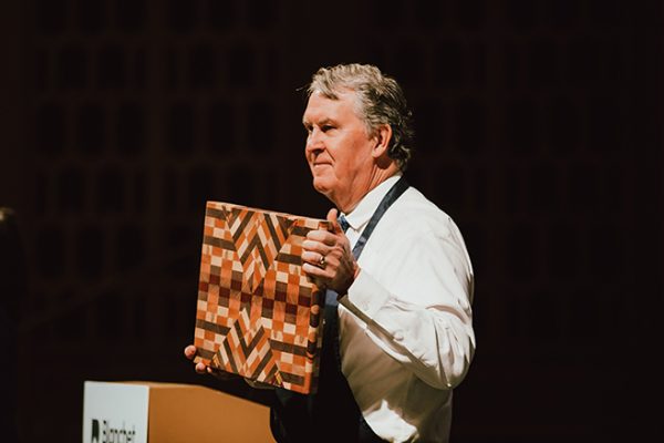 Emcee and board member Rich Ulring holds a custom wood board available to one lucky donor at the brunch on March 2, 2025.