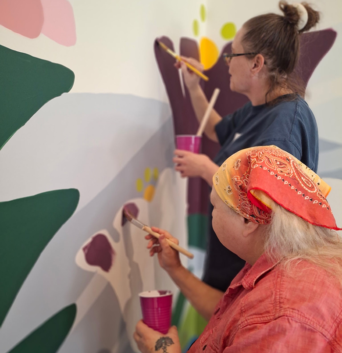 Volunteers paint a section of a mural designed by artist Sarah McCracken at Bethanie's Room women's shelter.